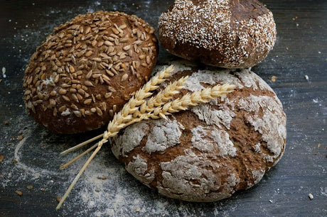 Assortment Of Artisanal Bread Loaves With Wheat Stalks In ’crusty Goodness’ Article.