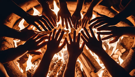 Hands reaching toward a campfire in a circle, symbolizing warmth and community.