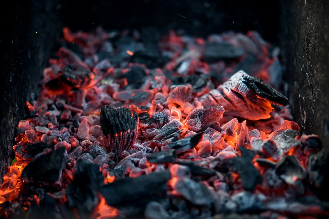 Glowing hot coals and embers from hillside woodfuels for premium charcoal butchery.