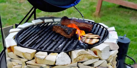 Circular Grill With Meat And Vegetables Cooking Over Flames In a Stone Or Brick Base.